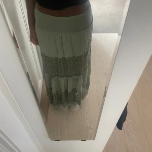 Grön långkjol med spetsdetaljer - Säljer en flowy grön långkjol med bred resår i midjan och fina spetsdetaljer 