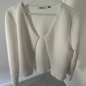 Vit korta från ONLY - Säljer en stilren vit kofta från ONLY. Koftan har lång ärm, öppen framtill utan knäppning och är tillverkad i ett mjukt, ribbat material. Perfekt för lager-på-lager och enkel att matcha med olika outfits. Koftan är i storlek L men det passar mig som brukar ha S i plagg!💗