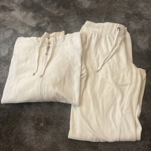 Vit hoodie med matchande mjukisbyxor - Säljer en vit hoodie med dragkedja och huva samt ett par matchande mjukisbyxor med dragsko i midjan. Hoodien har långa ärmar och fickor framtill. Settet är ifrån Cubus.