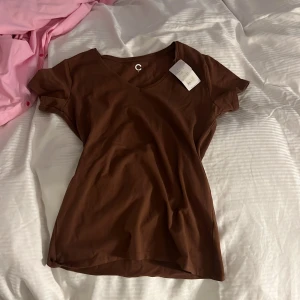 Brun v-ringad t-shirt från Cubus - Säljer en brun v-ringad t-shirt från Cubus i mjuk bomull. T-shirten har korta ärmar och en klassisk passform som passar perfekt till vardags. Enkel och stilren design utan mönster eller extra detaljer.