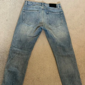 Blå jeans från Neuw Stockholm - Säljer ett par klassiska blå jeans från Neuw med raka ben och femficksmodell. Jeansen har raka ben och regular passform, de är tillverkade i denim med snygg tvättad look. Perfekta för dig som gillar stilrena och tidlösa jeans. (En mindre fläck, knappt synlig på framsidan av vänster ben) - kan skicka fler bilder vid förfrågan