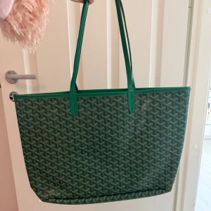 Grön shoppingväska  - Säljer en grön shoppingväska med klassiskt mönster och långa handtag. Väskan är rymlig och perfekt för att bära med sig allt man behöver. Den har ett elegant och tidlöst utseende med Goyards ikoniska tryck.