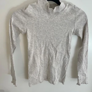 Ljusgrå ribbad polotröja från A better choice från Ellos i storlek 134/140 - Superskön ljusgrå ribbad polotröja från A better choice från Ellos! Tröjan är i storlek 134/140 och har lång ärm och en hög krage. 