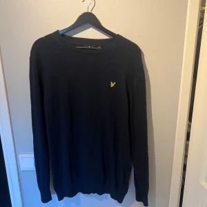 Svart tröja från Lyle & Scott - Säljer en marinblå långärmad tröja från Lyle & Scott med rund halsringning och den klassiska gula loggan broderad på bröstet. Perfekt för en stilren och enkel look. Aldrig använd, säljes på grund av fel storlek vid inköp. Dock är den ganska liten i storleken, känns inte som en xxl.
