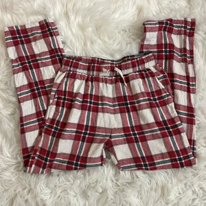 Mjukisbyxor - Säljer ett par mjuka och sköna byxor från Lindex i rödvitrutigt mönster. Byxorna har resår i midjan med snörning och är tillverkade i en återvunnen bomullsblandning. Perfekta för att chilla hemma eller som pyjamasbyxor.