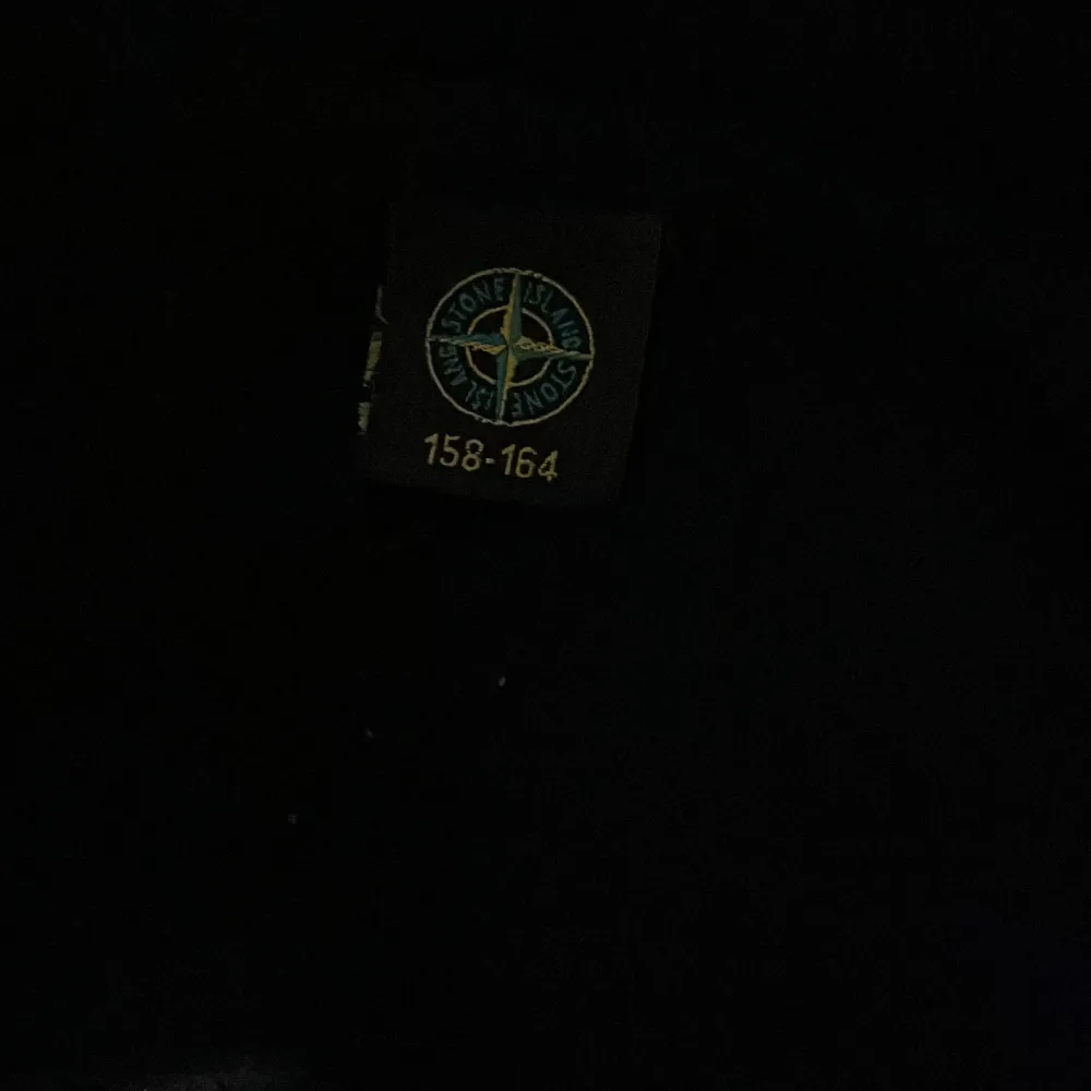 Säljer en svart hoodie från Stone Island med klassisk patch på ärmen och logga på insidan. Tröjan har huva och ribbade muddar vid ärmslut och nederkant. Perfekt för dig som gillar streetwear och vill ha något stilrent.. Neuletakit & Villapaidat.