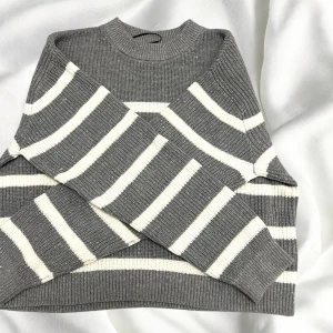 Randig stickad tröja – vit/grå  - Säljer en mysig stickad tröja i randigt mönster, vit och grå. Perfekt för kalla dagar eller som ett lager över en t-shirt. Den är både bekväm och stilren, och passar bra till både jeans eller mjukisbyxor.