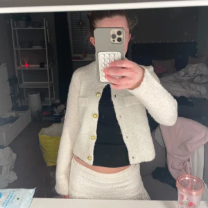 Vit stickad cardigan jacka från Uniq Studio - Säljer en fluffig vit stickad kofta från Uniq Studio med guldiga knappar framtill och två dekorativa fickor för att den inte kommer till användning längre. Storleken är 146/152 men passar perfekt för xs!🩷