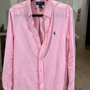 Rosa linneskjorta från Polo Ralph Lauren - Säljer en klassisk rosa skjorta från Polo Ralph Lauren i linne. Skjortan är nyskick inga defekter oxh jättefin. Säljer då den blivit för liten. Tveka inte vid eventuella frågor. 