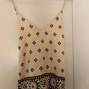 Beige topp med svarta mönster  - Säljer denna fina topp med svarta detaljer och som är korsad i ryggen.