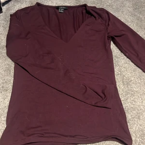 Vinröd långärmad topp från Amisu - Säljer en vinröd långärmad topp från Amisu i storlek M. Toppen har en djup v-ringning och är tillverkad i ett mjukt, stretchigt material. Perfekt att styla med jeans eller kjol för en snygg look.