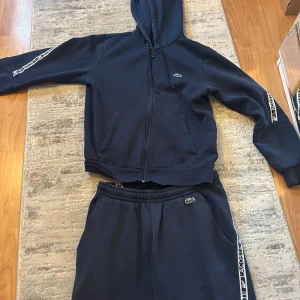 Mörkblå tracksuit från Lacoste - Snygg mörkblå tracksuit från Lacoste. Byxorna är i storlek M och koftan storlek S 