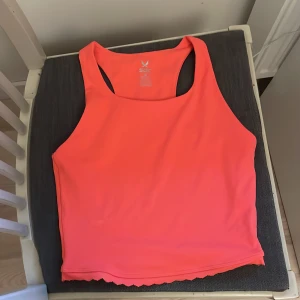 Koralrosa croppad linnetopp från SOC - Säljer ett korallrosa träningslinne  från SOC. Toppen har en brottarrygg och vågig kant nertill. Perfekt för träning. Materialet känns mjukt och stretchigt. (Använd 1 gång då jag provade den)