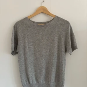 Grå kortärmad tröja från Uniqlo - Säljer en stilren grå tröja från Uniqlo i storlek XS. Tröjan har korta ärmar, rund halsringning och är tillverkad i ett mjukt material som passar perfekt till vardags. Enkel och tidlös design.