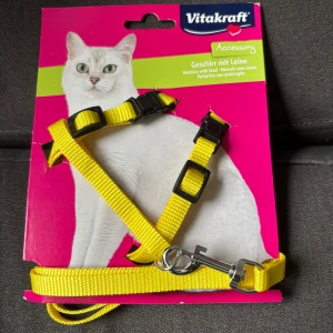 Gult koppel till katt från Vitakraft - gult koppel till katt Vitakraft med justerbara spännen och metallspänne. Bältet har en enkel design och är gjort i slitstarkt material.