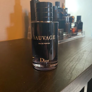 Sauvage Eau de Parfum från Dior - Säljer en lyxig herrparfym, Sauvage Eau de Parfum från Dior. Flaskan är elegant och mörkblå med svart lock och guldtext. Doften är modern och maskulin, perfekt för dig som vill sticka ut med en fräsch och kryddig signatur.