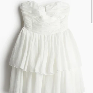 kort vit klänning utan band  - Säljer en söt vit klänning utan band och volangig kjol. Jag köpte klänningen på Hm men fick aldrig andvändning för den. Den går ungefär ner till precis innan knäna och är perfekt som skolavslutningsklänning. Hör av er vid frågor/bilder❤️