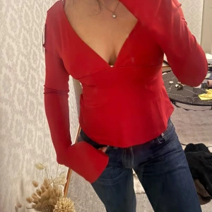 Röd topp med v-ringning och rosett baktill - Röd långärmad topp med v-ringning och knytrosett i ryggen. Prislapp kvar❤️