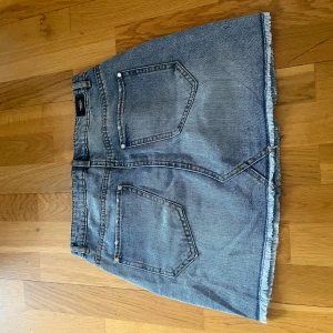 Blå jeanskjol med rå kant - Säljer en klassisk blå jeanskjol från Morgan med rå, fransad nederkant. Perfekt till vardags för en avslappnad look. Storlek 38 men är väldigt liten i storleken så skulle säga mer 34. Säljer för den är för liten 💘