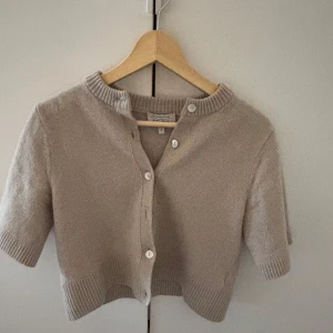 Beige stickad kofta  & Other Stories - Kortärmad beige stickad kofta från & Other Stories, Stockholm Atelier. Tröjan är andvönd 3 gånger, helt i nyskick och jätte fin till våren och sommaren!