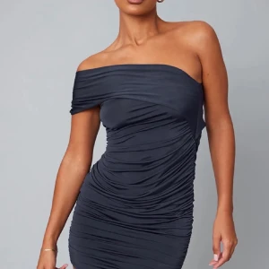 Svart oneshoulder klänning - Säljer en svart, tight oneshoulder klänning med draperad effekt. Klänningen har en kort längd och är tillverkad i ett stretchigt material som sitter snyggt på kroppen. Perfekt för dig som vill ha en stilren och trendig look.