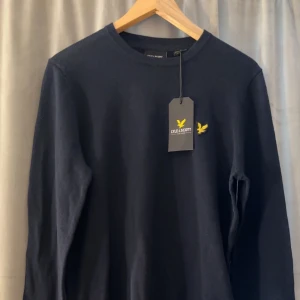 Mörkblå långärmad tröja från Lyle & Scott - Säljer en mörkblå långärmad tröja från Lyle & Scott i bomull och merinoull. Helt ny med prislappen kvar.