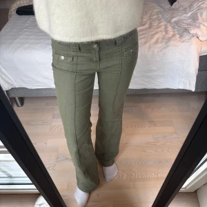 Gröna Jeans med fickor - Snygga olivgröna cargopants med raka ben och dekorativa fickor framtill med knappar. Byxorna har normal passform och är perfekta för en avslappnad stil. 