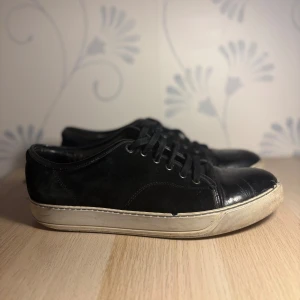 Lanvins  - Stilrena svarta sneakers med ovandel i mocka och detaljer i blankt skinn framtill. Klassisk vit sula och snörning för en clean look. Perfekta för dig som gillar minimalistisk stil med en twist.