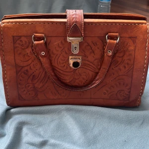 Handväska 70-tal - Supercool vintageväska i präglat skinn! Köpt på Beyond Retro för 350 kr. Den går inte riktigt att stänga helt (med klaspen, man måste typ pilla lite med nageln) men är ändå fett snygg som accessoar eller inredningsdetalj. 💼✨