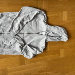 Grå hoodie med dragkedja från Weekday - Säljer en ljusgrå hoodie från Weekday, storlek M och den är ganska TTS, lite mer åt det lösa hållet dock. Men annars i fint skick. Tveka inte att höra av dig vid minsta lilla fråga!!