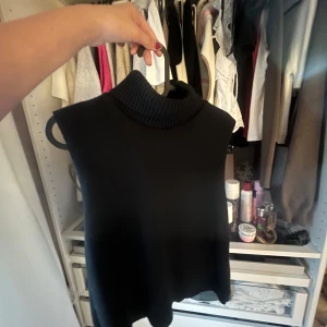 Svart stickad topp från Zara - Svart stickad polo topp från Zara. Modellen är ärmlös och har en clean, minimalistisk look. Toppen har en mjuk och skön kvalitet som ger en snygg stilren effekt😁💕💕Den är i storlek S🥰