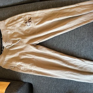Beige mjukisbyxor Calvin Klein Jeans M - Beiga mjukisbyxor från Calvin Klein Jeans med broderad logga på benet. Byxorna har resår och snörning i midjan, samt mjukt fleecefoder på insidan. Perfekta för chill dagar eller när du vill vara extra bekväm.