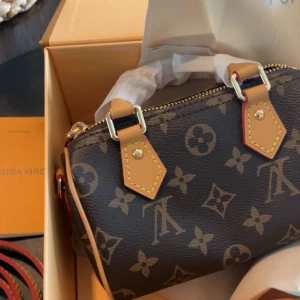 Louis Vuitton speedy nano axelväska - Säljer en  Louis Vuitton axelväska i klassiskt monogrammönster. Väskan är brun med beiga detaljer och har både handtag och justerbar axelrem. Tillverkad i skinn med guldfärgade metalldetaljer och dragkedja upptill. Perfekt storlek för det viktigaste. Har endas ägt denna i ca 2 månader och insett att det inte riktigt är min stil. Har fått den i present och inte lagt några egna pengar på den varav priset.😊Box och dustbag medföljer. 