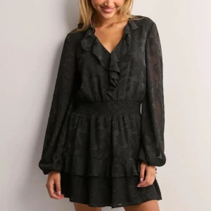 Svart kortklänning med volang från Nelly - Supersnygg svart kortklänning från Nelly med v-ringning, volangdetaljer och långärmade ärmar. Klänningen är o andvänd och har prislappen kvar. Säljer då den aldrig kommit till användning. Bara att höra av sig om man undrar något!// Amanda💕