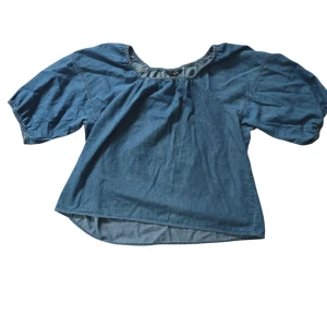 Blå blus i jeanslook från KappAhl XL - Säljer en blå blus från KappAhl i jeanslook med rundad hals och korta puffärmar. Blusen har resår vid halsringningen och är tillverkad i ett mjukt jeanstyg som ger en avslappnad vibe. Perfekt för dig som gillar denimstilen!