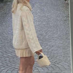 Beige handväska i skinn från Arket - Minimalistisk beige handväska från Arket i skinn. Väskan har ett kort handtag och justerbar axelrem.