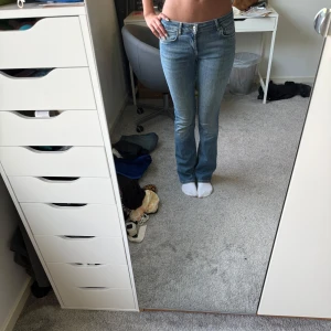 Blå bootcut jeans lowwaist - Säljer ett par klassiska blå jeans med bootcut-snitt och lowwaist. Jeansen har fem fickor, dragkedja och knapp framtill. Perfekta för dig som gillar en tidlös look med lite utsvängda ben. Snygga till sneakers eller boots!