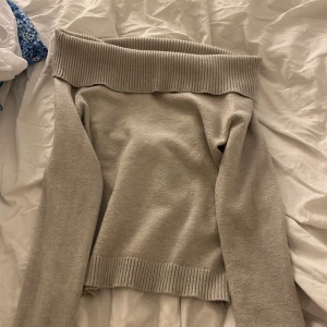 Beige offshoulder stickad tröja Gina Tricot - Superfin beige stickad tröja från Gina Tricot med bred ribbad offshoulder-krage och långa ärmar. Perfekt för dig som gillar en chill men ändå snygg look. Mjuk och skön, passar till allt och är lätt att styla med dina favoritjeans.