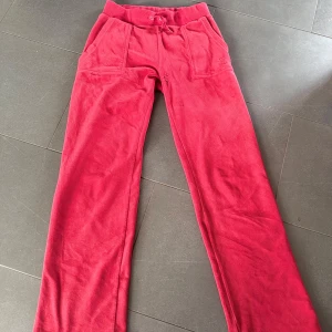 Röda fleecebyxor med snörning - Mysiga röda mjukisbyxor i fleece med raka ben, snörning i midjan och stora fickor fram. Baksidan har två fickor med knappar. Perfekta för chill eller hemmadagar. Lite i sönder nere vid och där fram.PRIS KAN DISKUTERAS VID SNABB AFFÄR