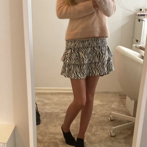 Zebramönstrad volangkjol - Supersöt kort kjol med zebramönster i svart och vitt. Kjolen har bred resår i midjan och dubbla volanger som ger en riktigt snygg och lekfull look. Perfekt för dig som vill sticka ut lite extra! Passar till både sneakers och boots.