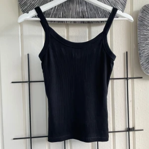 Svart ribbat linne från Gina Tricot - Ett ribbat linne från Gina Tricot, Basically Basics-kollektionen. Toppen har smala axelband, perfekt för lager-på-lager eller sommarens varma dagar. Enkel och stilren modell som är lätt att matcha med allt. <3