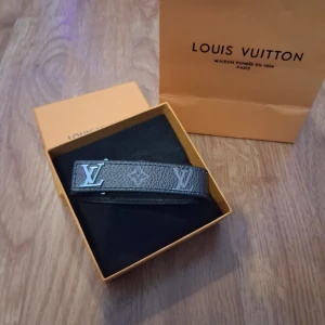 Louis Vuitton grått skinnarmband - Snyggt armband från Louis Vuitton i grått skinn med klassiskt LV-monogram och silverfärgat LV-spänne. Armbandet har en stilren och exklusiv look, perfekt för dig som gillar designeraccessoarer. Levereras i originalask.