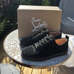 Svarta sneakers med nitar - Hej jag säljer ett par svarta sneakers med snörning och coola svarta nitar på tån och framtill. Skorna har rund tå och platt sula, och är tillverkade i mocka. Box, kvitto och dushbag ingår även de. Hör av er om ni har några funderingar☺️