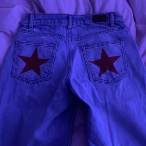 Blå jeans med röda stjärnor bak SUBDUED - Säljer ett par blå jeans från Subdued med low Rise och straight leg  samt röda stjärnor på bakfickorna. Klassisk baggy lowrise med normal passform och midja. 