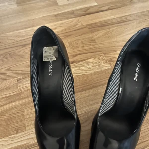 Svarta pumps från Graceland - Snygga svarta pumps från Graceland med hög klack och glansig finish. Perfekta för en elegant look. Innersulan har ett randigt mönster för extra stil.