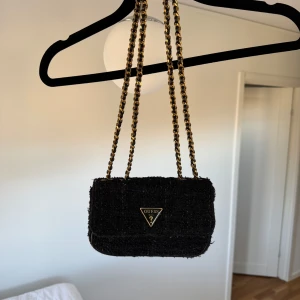 Svart axelväska från Guess - svart axelväska från Guess med kedjehandtag som är justerbar. Nypris för denna är 1200kr, säljer för 400kr