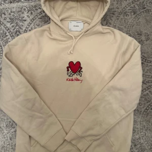 Axel Arigato Hoodie - Säljer en stilren beige hoodie från Axel Arigato från Keith Haring collaben. Fick i julklapp för ett år sedan men använd några gånger hemma bara då det inte är min stil. Nypris 2500