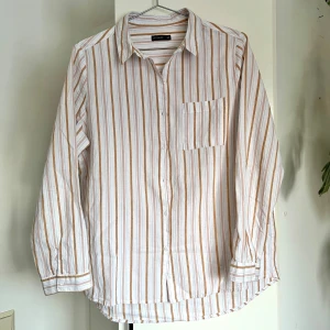 Randig bomullsskjorta - Snygg randig skjorta i vita, beigea, blåa och rosa ränder. Passar utmärkt som oversized också. Perfekt för en stilren look. I fint skick.