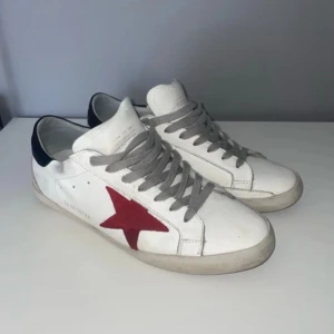 Vita sneakers från Golden Goose - Snygga vita sneakers från Golden Goose med en röd stjärna på sidan. Ny pris 3799kr mitt pris 1899kr, box dust bag o allt og medföljer! Hör av vid frågor o fler bilder ✅, byten kan också vara intressant 
