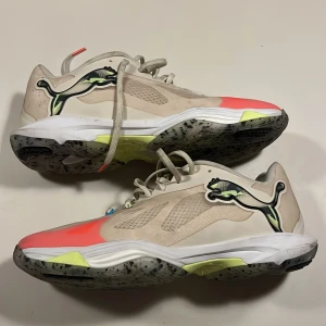 Beige sneakers med neonrosa detaljer - Säljer ett par handbollsskor från Puma. Använda 1  träning. 10/10 skick. Nypris 1800. Skriv vid fler frågor.!!